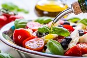 Olivenöl wird über einen frisch zubereiteten Salat gegossen. Olivenöl wird über einen frisch zubereiteten Salat gegossen.